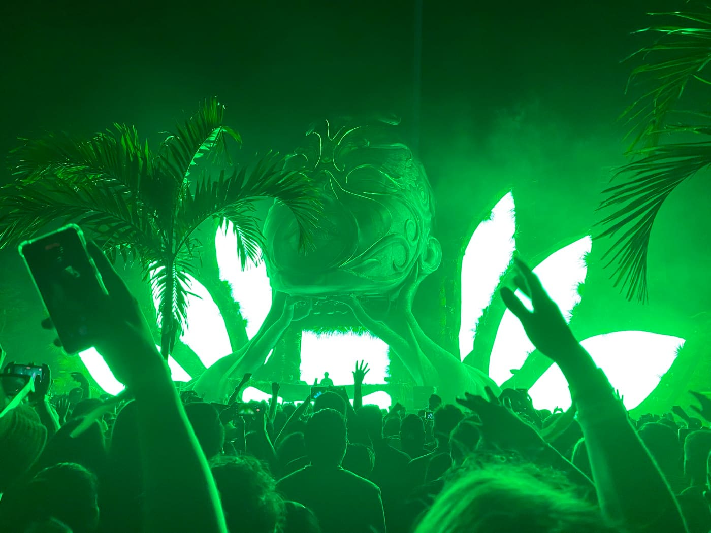 Escenario iluminado en verde con multitud celebrando en un festival MATIE en Tulum